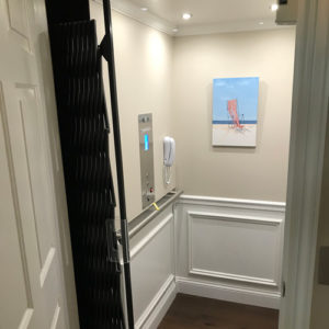 A residential elevator with phone and picture on wall.