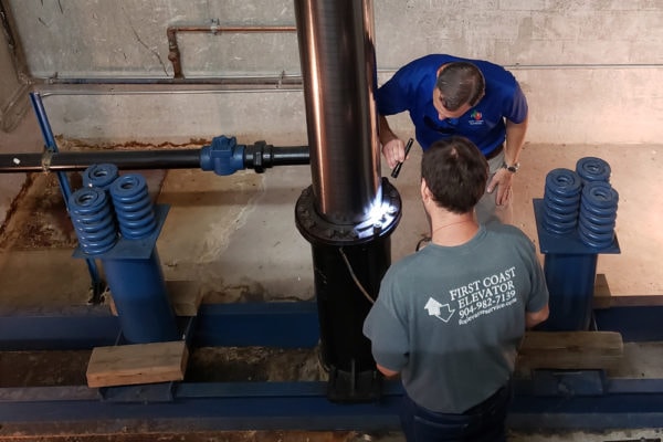 Two men inspecting an elevator tube.