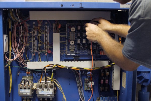 A man testing an elevator electrical panel.